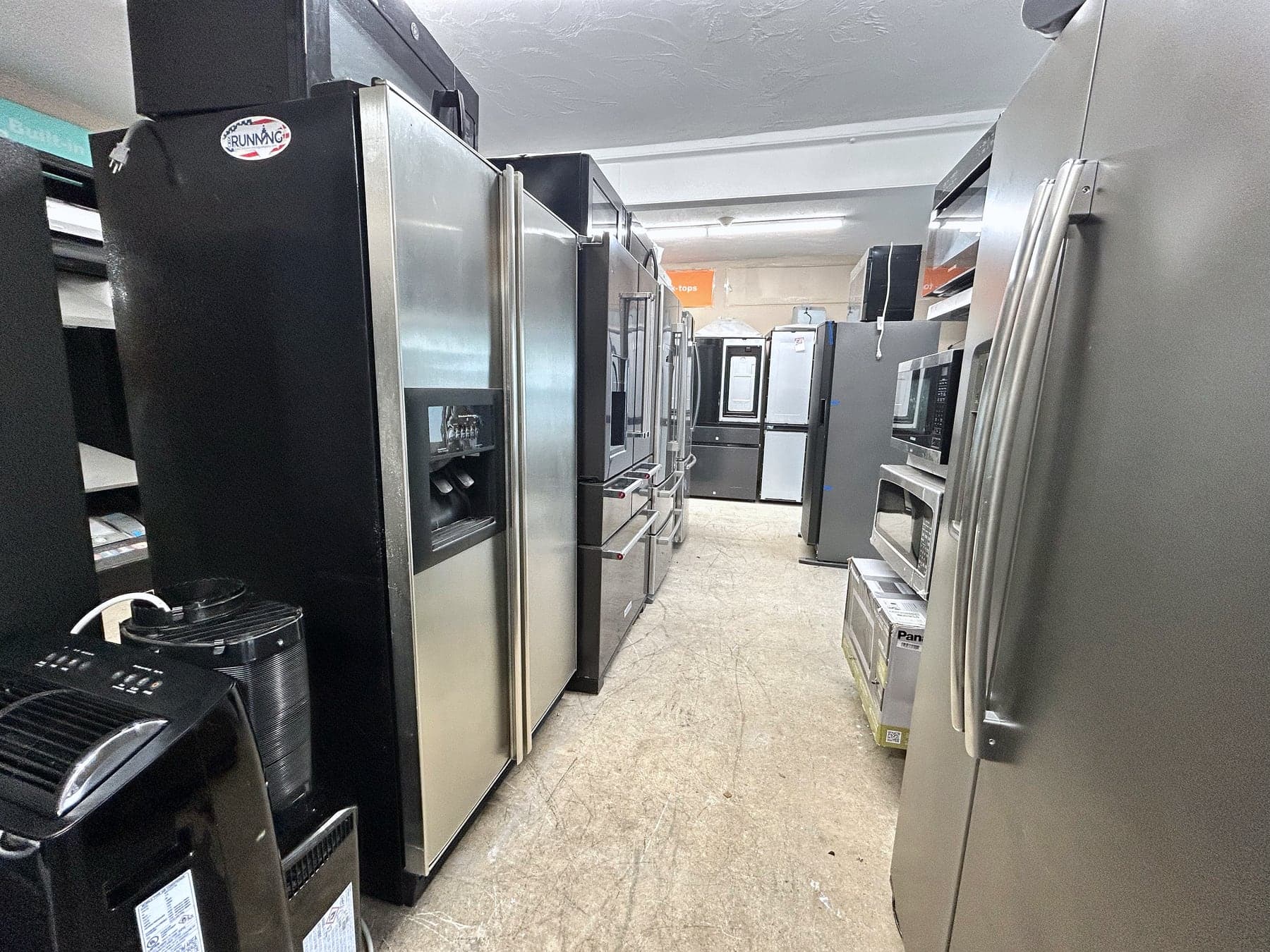 An aisle of stainless steel refrigerators in the showroom