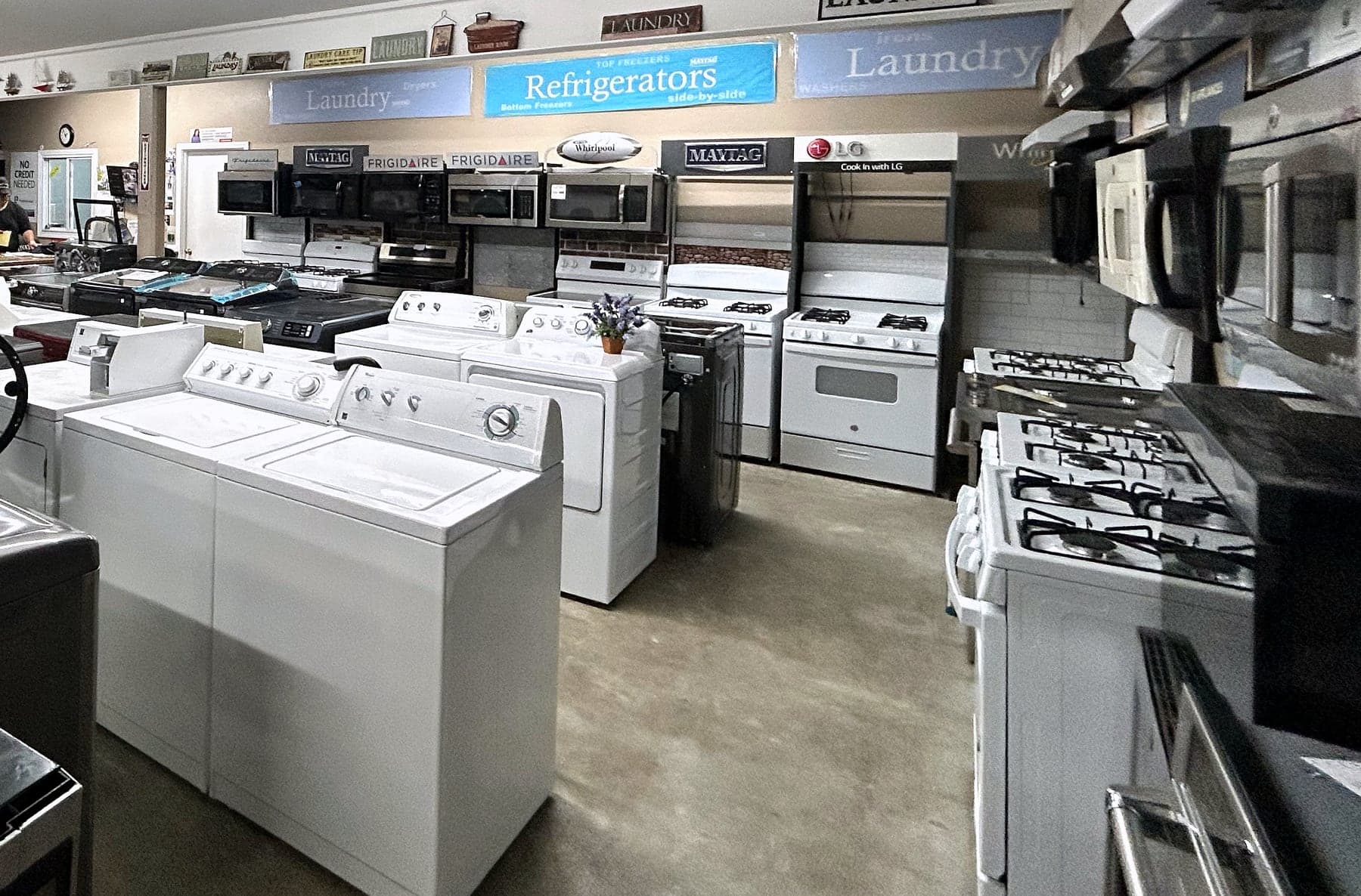 Laundry aisle of the showroom, washers and dryers under brand signage
